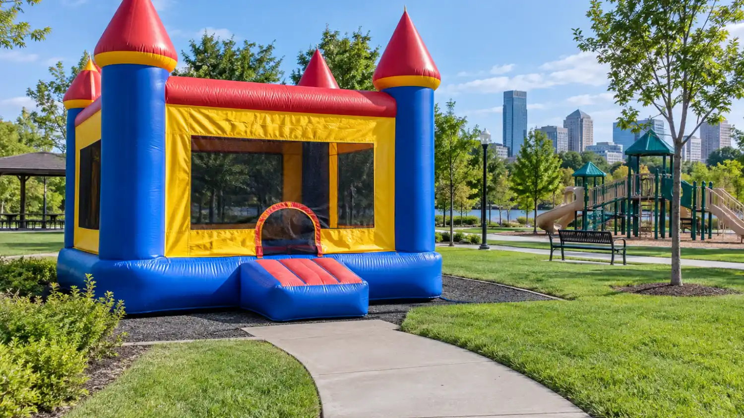 commercial inflatable bounce castle set up in a public city park with an accessible paved pathway leading to the entrance
